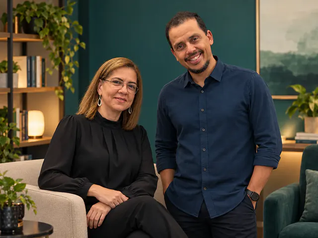 Duas pessoas adultas conversando em uma sala com plantas